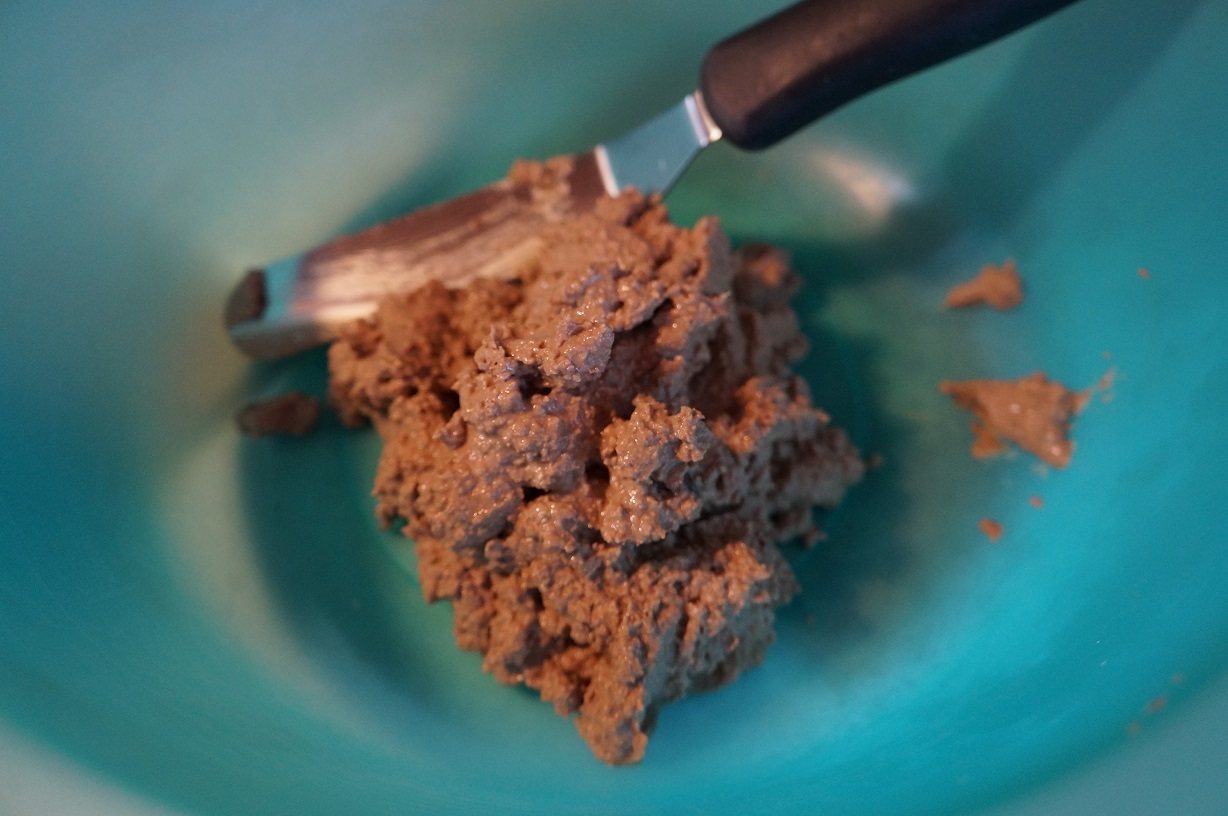 cooked liver ground up into a paste inside a green bowl with a flat spatula nearby