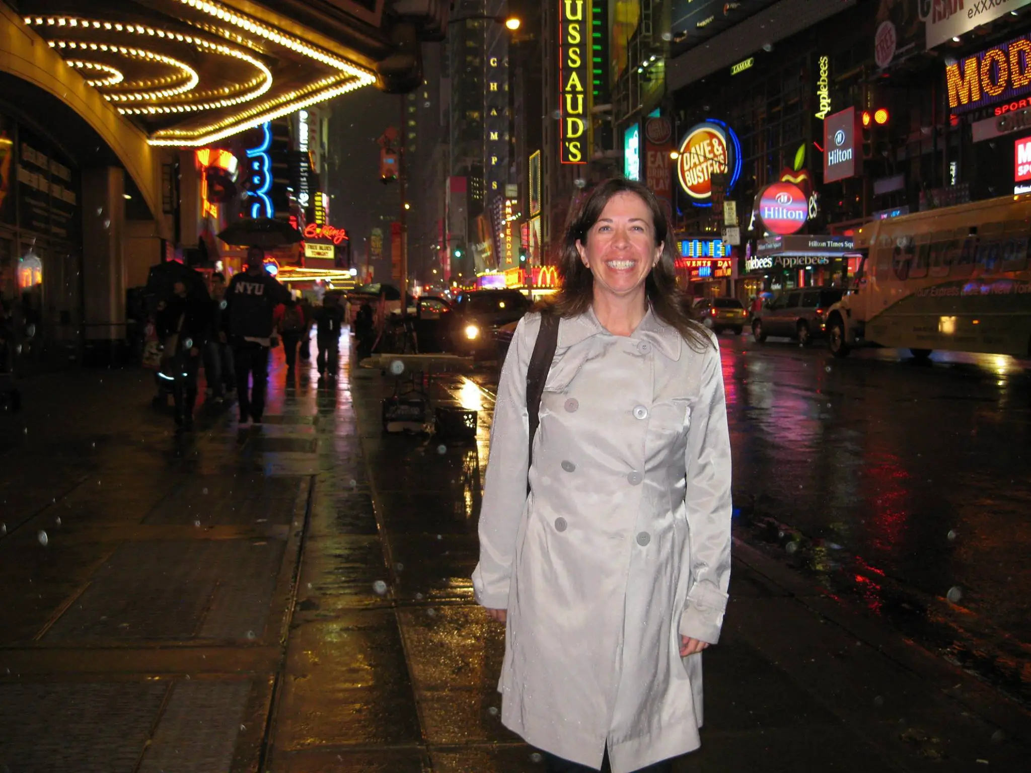 white woman brown hair silver trench coat in the rain at Times Square